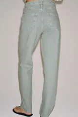 Jeans de tiro bajo y corte recto, confeccionados en denim con estampado de rayas verticales y efecto lavado. Presenta cinco bolsillos, trabillas en la cintura, cierre frontal con cremallera y botón, y un detalle de rotura en la parte delantera.