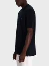 Remera de corte regular, color negro, con cuello redondo y detalle de monograma metálico en el pecho.