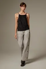 Top halter negro de viscosa, sin mangas, con tirantes finos y cobertura completa de ojalillos metálicos plateados.