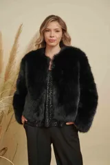 Abrigo corto de piel sintética en tono beige, con cuello redondo y mangas largas. Diseño de corte recto y textura suave.