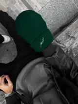 Gorro de lana verde oscuro con dobladillo y bordado blanco con la palabra "Just".