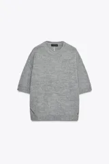 Jersey de punto gris, cuello redondo y manga corta, con calce oversize y terminaciones en rib.