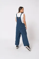 Mono largo de denim azul, corte oversize, con tirantes regulables y bolsillos laterales.