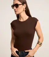 Blusa de canalé color marrón, de corte ajustado, cuello redondo y mangas sisa con hombros ligeramente estructurados.