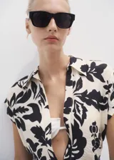 Vestido midi de viscosa con estampado floral en color crudo y negro, cuello camisero, manga corta, cierre frontal con botones y cinturón ajustable del mismo tejido.