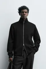 Chaqueta regular fit de cuello subido, confeccionada en tejido técnico interlock de algodón con elasticidad. Presenta cierre frontal con cremallera, manga larga con puños en rib y bolsillos de vivo en la cadera.