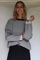 Buzo oversize de tejido de punto con diseño jacquard en mangas y espalda, cuello redondo y detalle de etiqueta de cuero sintético en el ruedo.