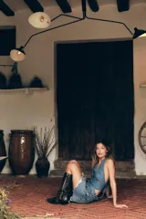 Chaleco de denim azul con cuello halter y escote pico. Presenta falsos bolsillos de vivo en el delantero y cierre frontal con botones metálicos.