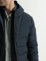 Campera acolchada con capucha integrada y cuello alto. Presenta cierre frontal completo, bolsillos laterales con cierre y puños con terminaciones elásticas para mayor protección contra el frío.