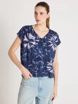 Remera de algodón y lino, con escote en V y diseño amplio de hombros caídos, decorada con estampado tie-dye en tonos de azul y rosado.