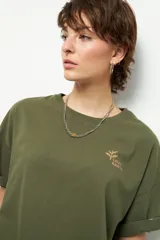 Remera negra de corte oversize con cuello redondo y manga corta. Presenta un pequeño estampado dorado en el pecho con la frase "love earth" y un símbolo de hojas.
