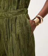 Pantalón wide leg de poliéster color verde militar, con textura plisada y estampado sutil de hojas, cintura elástica y caída fluida.