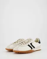 Championes deportivos de estilo retro color blanco con detalles en negro, suela fina color caramelo, capellada de cuero y nylon, lengüeta semitransparente acolchada, cordones bicolor intercambiables y cuello acolchado.