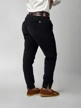 Pantalón de pana negro de corte recto, con bolsillos laterales y traseros. Se ajusta a la cintura con cinturón de cuero negro.