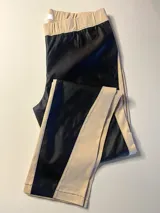 Pantalón ajustado con frente de cuerina sintética negra y parte trasera y laterales de gabardina color beige. Cuenta con cintura elástica.