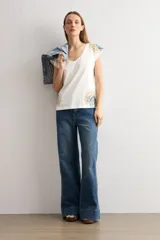 Remera blanca de manga corta, con escote en V y detalles de estampa paisley en los hombros y en el borde inferior.