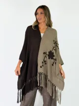 Ruana de punto bicolores, dividida en marrón oscuro y verde militar, con mangas amplias, flecos en el ruedo y delicados bordados florales oscuros en el lateral.