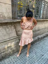 Conjunto de dos piezas compuesto por un top de un solo hombro con volados y una falda corta con ruedo asimétrico, confeccionado en tela satinada con estampado floral en tonos verde y dorado.