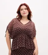 Blusa tipo bata confeccionada en tule con forro interior, escote en V, mangas cortas con detalle de lazo y cintura fruncida. Presenta un estampado geométrico tipo pañuelo.