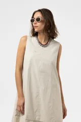 Vestido midi de silueta amplia y relajada, sin mangas, con escote redondo y costuras decorativas. Presenta una falda con corte y volumen.