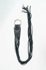 Cinturón negro de cuero con diseño de flecos largos, decorado con tachas metálicas plateadas en la base y cierre de doble argolla metálica.