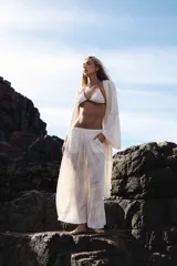 Pantalón ancho de lino color crema, con cintura elástica y bolsillos laterales. El tejido presenta un patrón de rayas finas verticales.