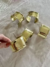 Pulsera rígida dorada, tipo brazalete, con terminaciones redondeadas.