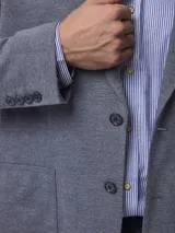 Blazer de piqué en color azul, con solapa clásica, cierre frontal de dos botones y bolsillos laterales de parche.