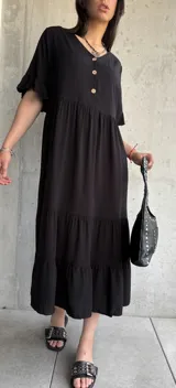 Vestido midi negro con botones frontales, mangas cortas con volados y falda con volados escalonados.
