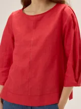 Blusa de algodón color rojo con escote redondo, mangas tres cuartos abullonadas y costura vertical decorativa en el centro.