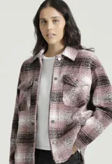 Campera Levis tipo shacket a cuadros rosas, negros y blancos, con cierre frontal con botones a presión, cuello camisero, bolsillos con solapa abotonada en el pecho y corte recto.