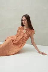 Vestido largo color salmón con estampado abstracto, escote con lazo y mangas cortas. Diseño fluido con frunces en el pecho.