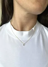 Collar dorado con cadena fina y dije de circonita transparente.