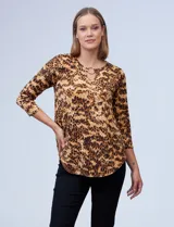 Blusa de seda fría con estampado animal print en tonos marrones. Tiene cuello redondo con escote en V y aro metálico decorativo.