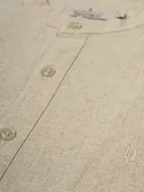 Camisa de lino color crudo, de manga larga con puños abotonados y cuello mao.