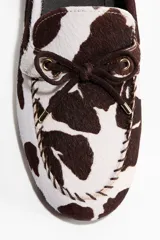 Zapatos náuticos de cuero con estampado animal print tipo vaca, con cordones delanteros y costuras decorativas.