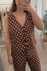 Blusa marrón con lunares blancos, escote en V y sin mangas.