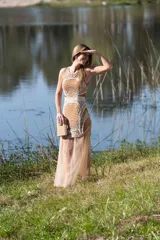 Vestido largo sin mangas, con base de seda natural, bordado a mano con canutillos y paillettes en tonos mostaza y crudo, y falda de tul transparente por debajo.