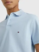 Chomba celeste de Tommy Hilfiger, corte regular, con cuello tipo chomba, cartera de dos botones, logo bordado en el pecho y detalles distintivos de la marca.