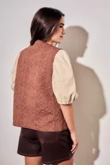 Chaleco sin mangas de color marrón, con diseño acolchado y bordados florales en toda la superficie. Presenta un corte recto y terminaciones con ribetes al tono.