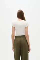 Body de manga corta al cuerpo, color blanco, con cuello redondo y cierre inferior con broches.