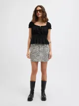 Minifalda de denim con estampado de leopardo en tonos grises y blancos, tiro medio, con cierre de cremallera y bolsillos delanteros y traseros.