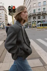 Blazer de corte oversize en color gris jaspeado, con cuello solapa, hombreras y cierre frontal cruzado con botones. Cuenta con bolsillos delanteros con solapa.