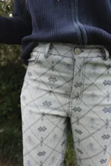 Jean de tiro alto con corte straight flare, confeccionado en denim de algodón con estampado geométrico de rombos y motivos florales en tonos azulados.