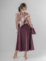 Camisa de seda italiana con diseño reversible, permitiendo usar el lazo en la parte frontal o posterior. Presenta un estampado sutil con motivos abstractos y animal print, cuello alto con volados, mangas largas con puños elásticos y corte holgado.