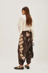 Pantalon de corte holgado tipo bombacho con estampado batik tradicional en tonos azul marino, beige y dorado. Presenta cintura elástica y diseño fluido.
