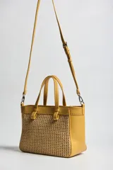 Cartera tipo tote color amarillo con detalles en textura tejida en la parte frontal y trasera, asas de mano y correa de hombro ajustable y desmontable. Incluye aplique metálico con el logo de la marca.