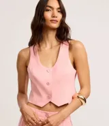Chaleco cropped sastre color rosado, confeccionado en viscosa, con escote en V, botones delanteros y pences.