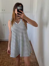 Vestido corto blanco con rayas horizontales negras, escote en V y sin mangas.