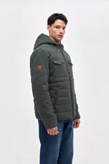 Campera de gabardina capitoneada con interior forrado en nylon. Presenta capucha fija, bolsillos frontales en el pecho con solapa y bolsillos laterales con cierre. Cuenta con cierre frontal central.